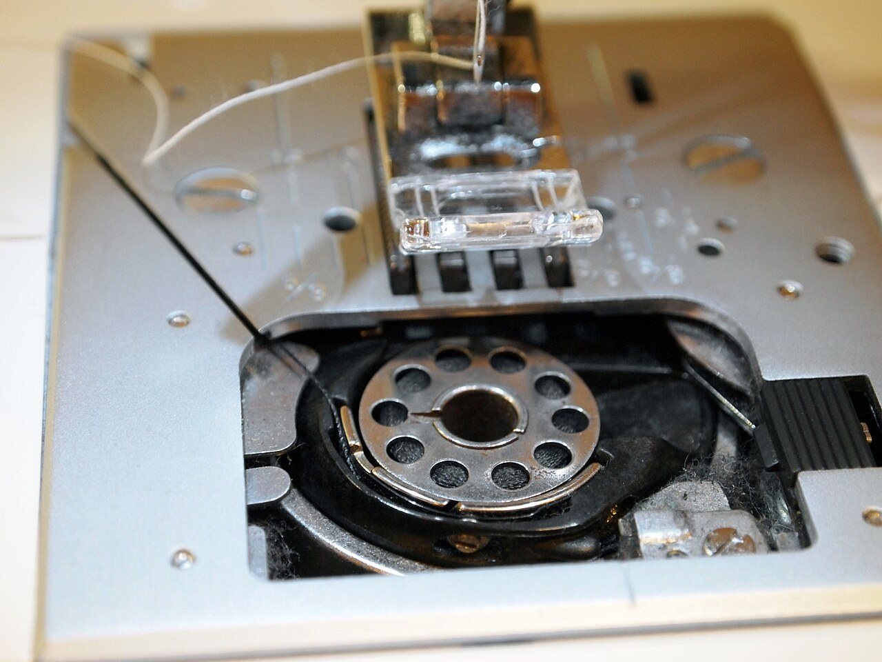 Sewing machine bobbin under the foot plate.